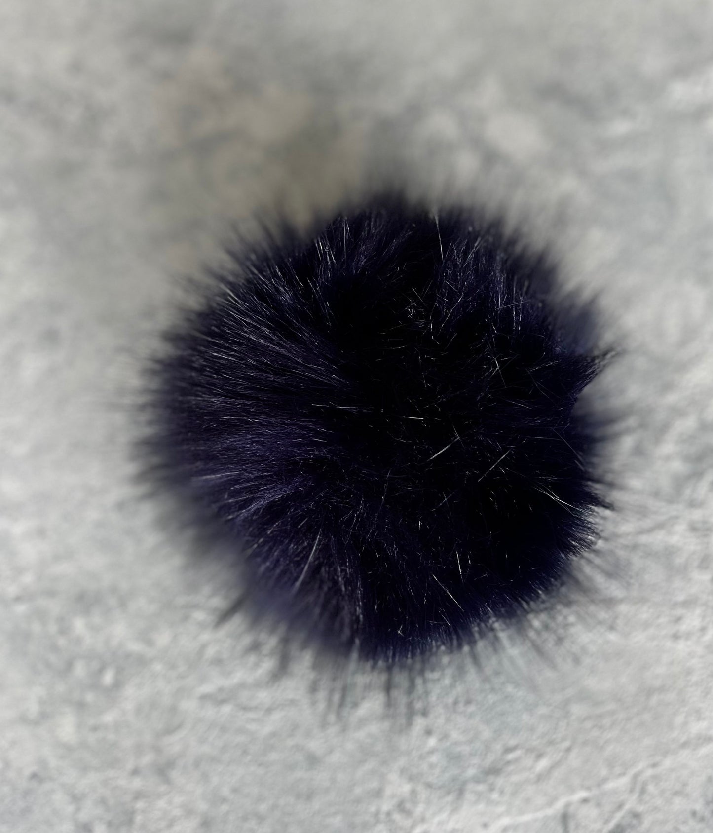Navy cashmere plain knit beanie with an orange smiley embellishment & faux fur pom