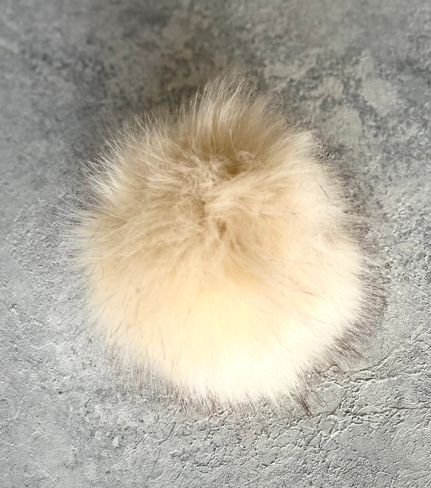 Navy cashmere plain knit beanie with an orange smiley embellishment & faux fur pom